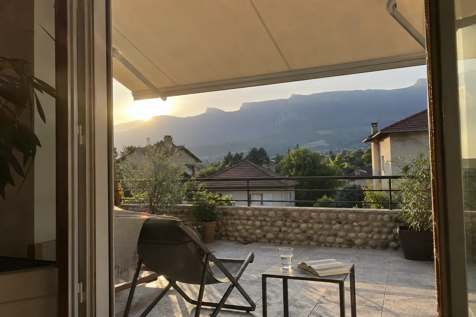 Store banne déployé au-dessus d’une terrasse au soleil couchant, chaise longue et table basse dans l’ombre