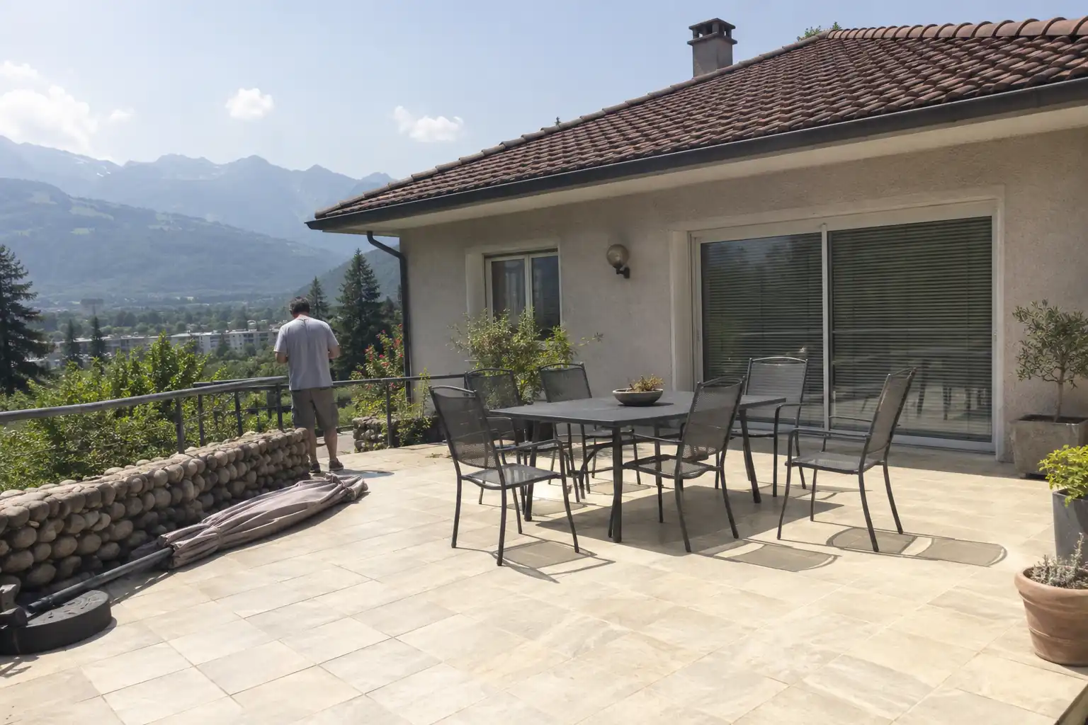 Terrasse dallée en plein soleil sans aucune protection, table et chaises exposées devant la maison